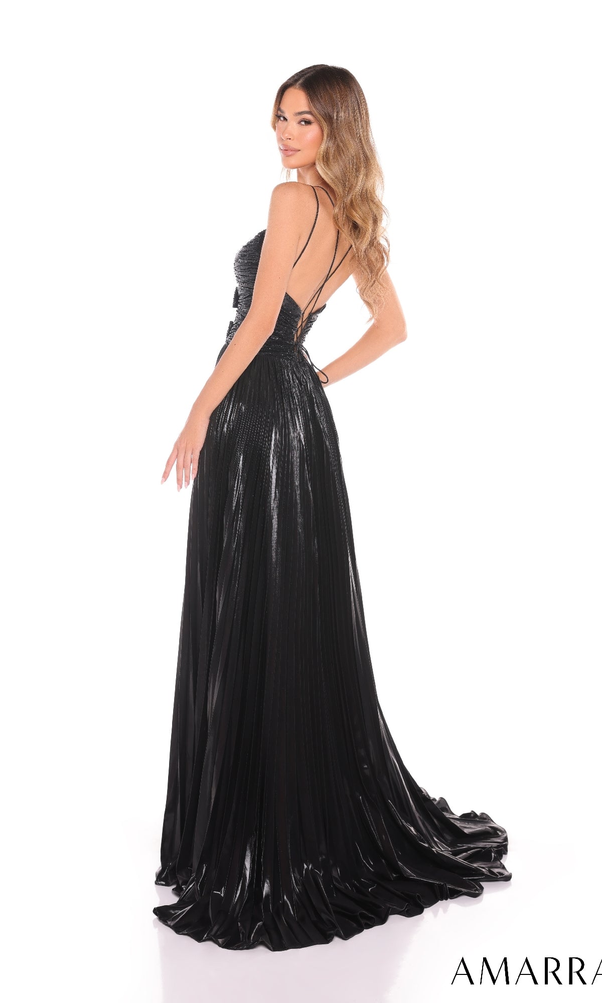 A woman stands against a white background wearing the Amarra 88435 Long Prom Dress?a black, floor-length pleated gown with a v-neckline, thin straps, and an open back.